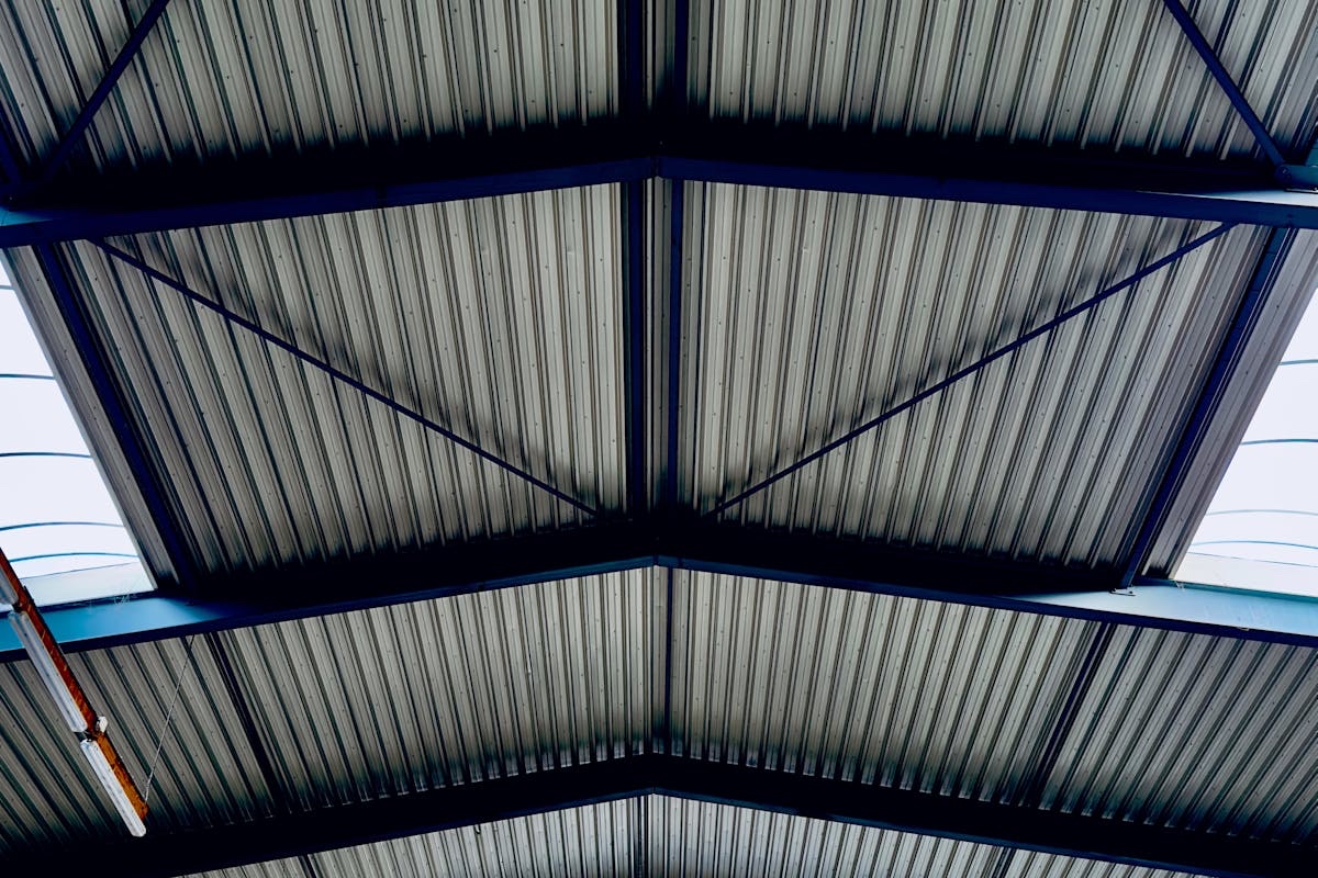 Interior de galpão industrial com telhado metálico trapezoidal — estrutura de telha metálica vista de dentro do armazém